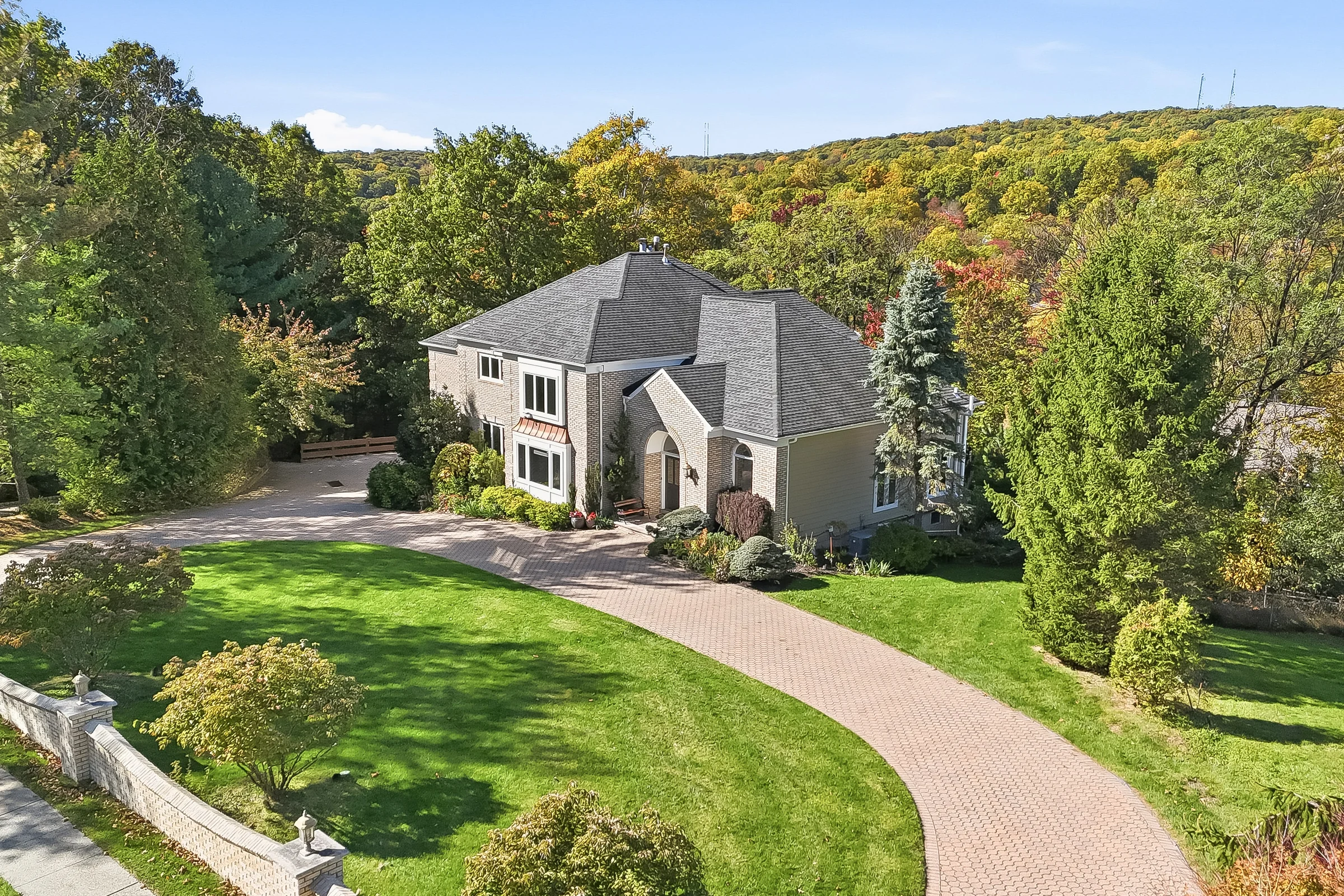 Aerial view of 12 Tree Top Terrace, its circular drive, and leafy grounds